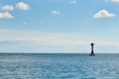 Lighthouse by sea against sky