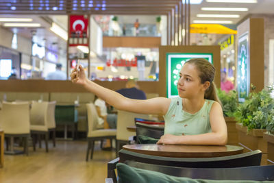 Young woman sitting on table in restaurant