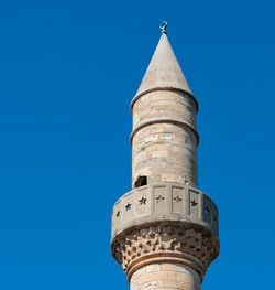 Low angle view of tower amidst buildings against clear blue sky