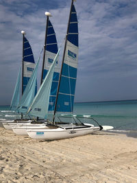 Sailboats moored on beach against sky