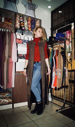 Full length of young woman standing at clothing store
