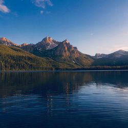 Scenic view of lake by mountains against sky