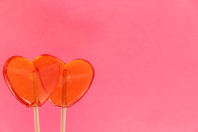 Close-up of heart shape on pink balloon against red background