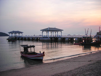 Pier in sea against dramatic sky during sunset