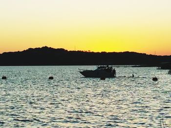 Silhouette boats in sea against clear sky during sunset