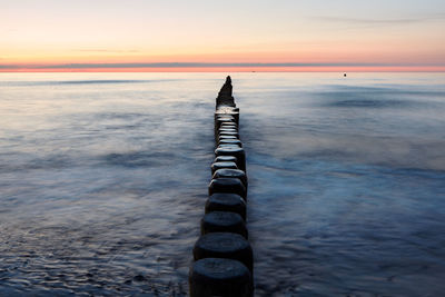 Poles in row at calm sea