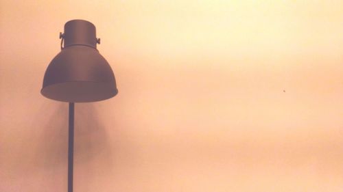 Low angle view of illuminated street light against wall