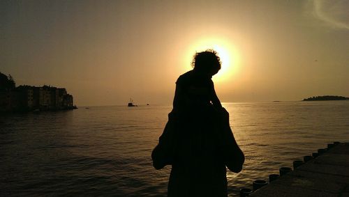 Silhouette woman standing by sea against sky during sunset