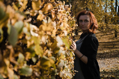 Side view of woman standing by plants during autumn