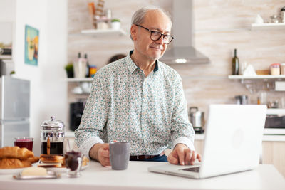 Smiling man using laptop on table at home