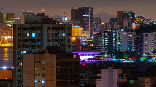 Illuminated buildings in city against sky at night