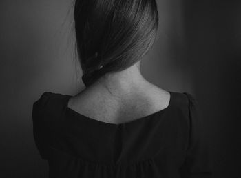 Rear view of woman by wall in dark