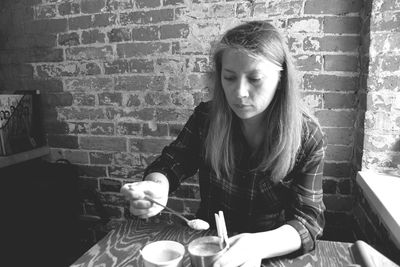 Woman having coffee at table against wall