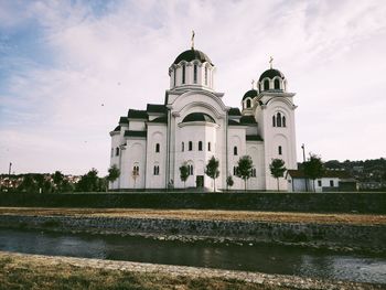 View of building by lake against sky