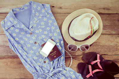 Directly above shot of clothing with hat and passport on hardwood floor