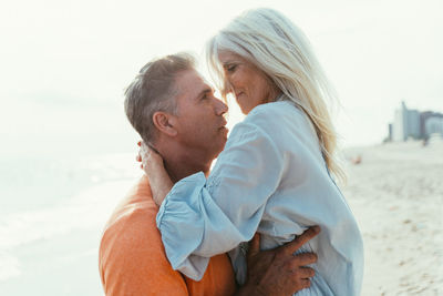 Side view of couple embracing at beach