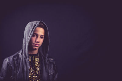 Close-up of young man standing against black background