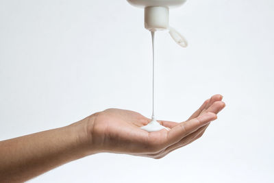 Close-up of hand holding umbrella against white background