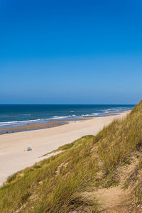 Scenic view of beach against clear blue sky