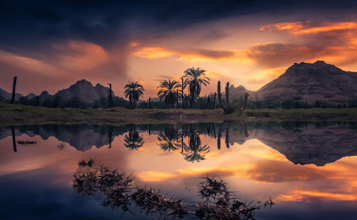 Scenic view of lake by mountains against orange sky