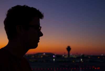 Portrait of young man looking away against sky during sunset