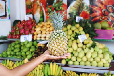 Cropped hand of woman holding pineapple at market stall