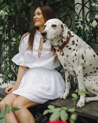 Portrait of woman with dogs sitting on bench on street