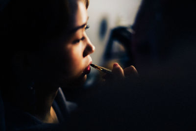 Close-up of young woman applying lipstick