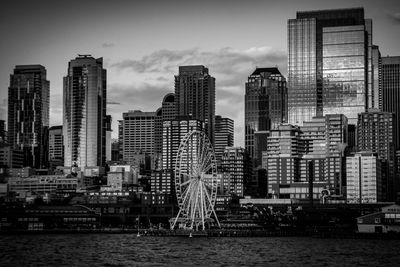 Modern buildings by river against sky in city