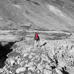 Rear view of backpack male hiker walking on field against mountain