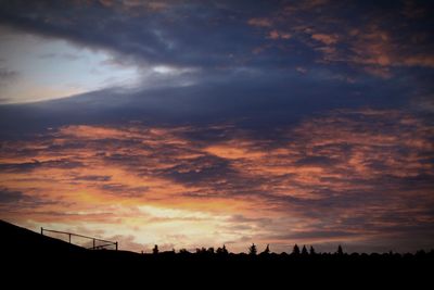 Silhouette landscape against dramatic sky during sunset