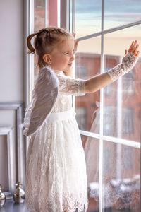 Side view of young woman standing at home