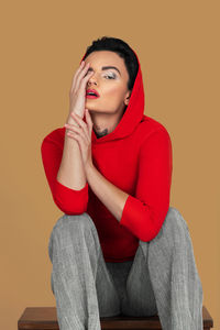 Young woman sitting on sofa against yellow background