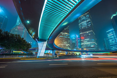 Light trails on road amidst illuminated buildings in city at night