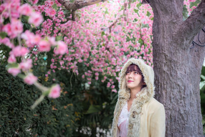 Woman standing by pink flowering tree