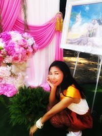 Portrait of smiling woman standing by pink flowering plants