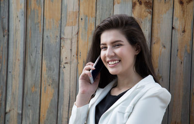 Portrait of smiling young woman using smart phone outdoors