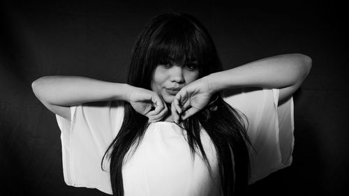 Portrait of woman with long hair standing against black background