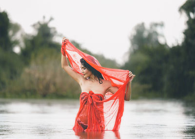 Woman with red umbrella standing in water