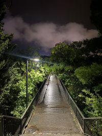 Footbridge amidst trees against sky