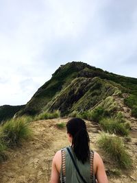 Rear view of mature woman looking at mountain against sky