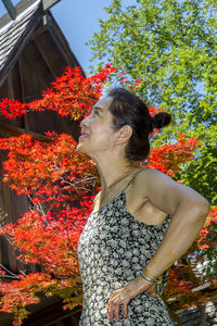 Full length of young woman standing against tree