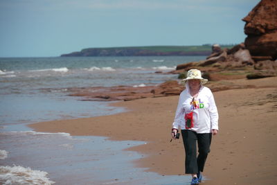 Woman walking on beach against sky