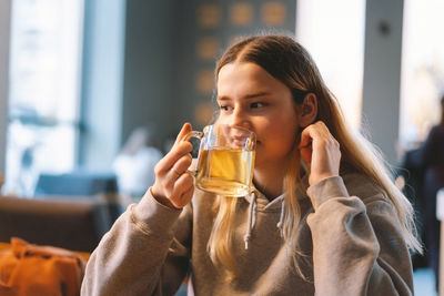 Portrait of a joyful teengirl enjoying a cup of tea at cafe