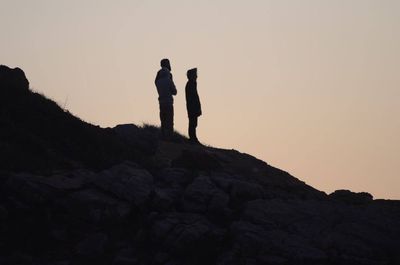 Low angle view of silhouette man standing on cliff against clear sky