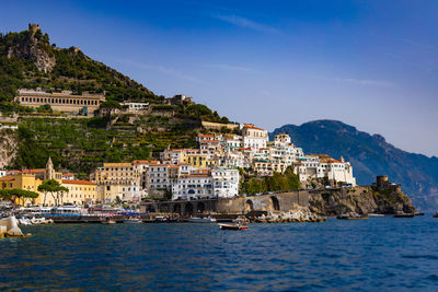 Buildings by sea against sky