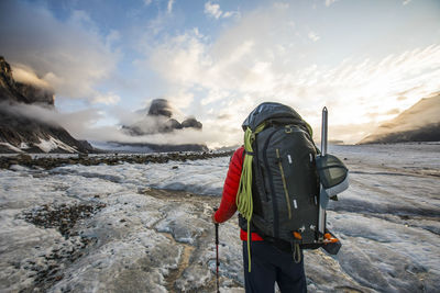 Rear view of backpacker hiking across glacier on baffin island.