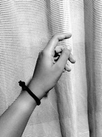 Cropped hand by curtain