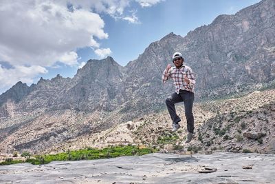 Full length of man standing on rock against sky