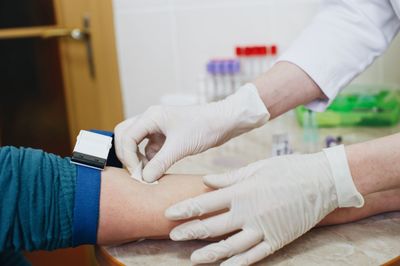 Cropped hands of doctor sticking paper on patients hand during blood test